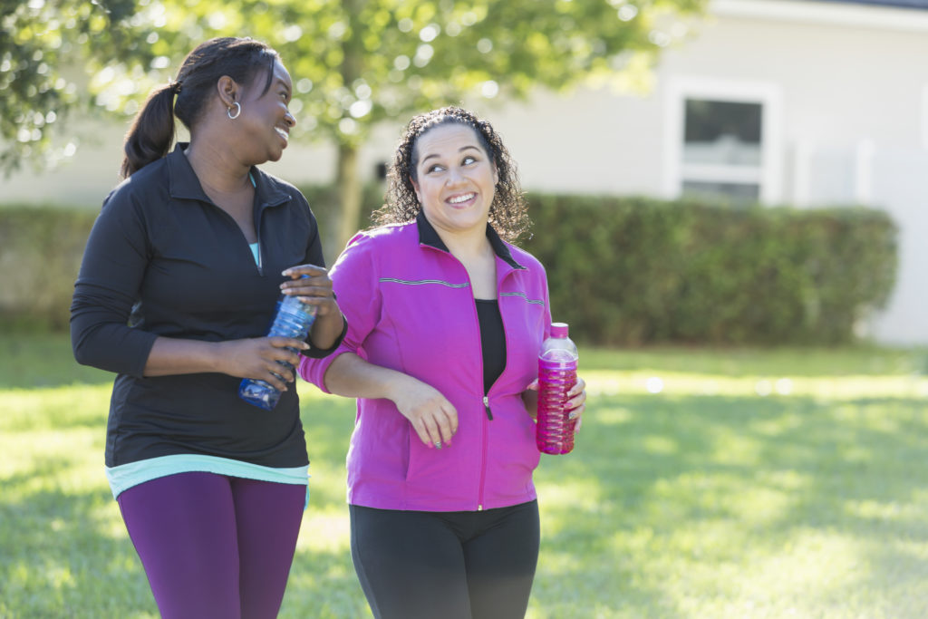 Two multi-ethnic women drinking sports drinks outdoors
