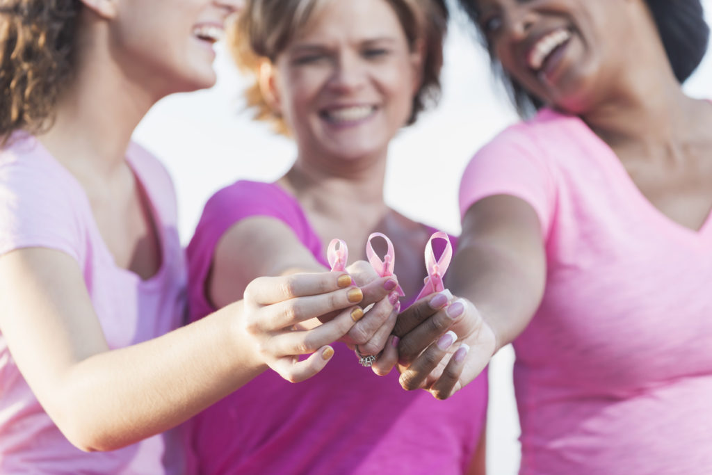 Multiracial hands holding breast cancer awareness ribbon